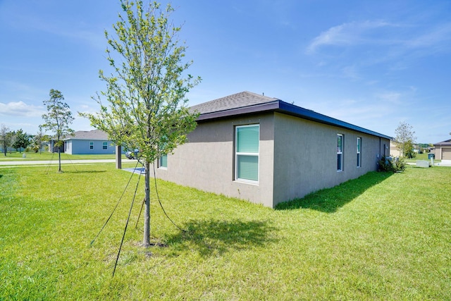 view of side of home featuring stucco siding and a lawn