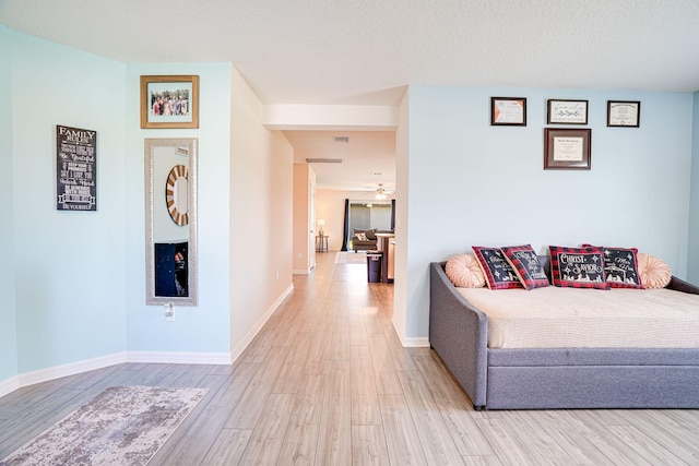 living room featuring ceiling fan, a textured ceiling, baseboards, and wood finished floors