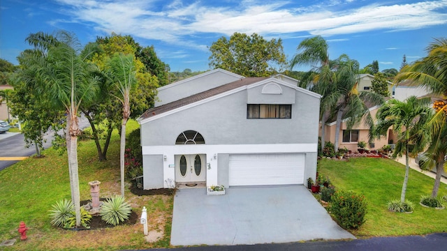 view of front of house featuring a front lawn, an attached garage, driveway, and stucco siding