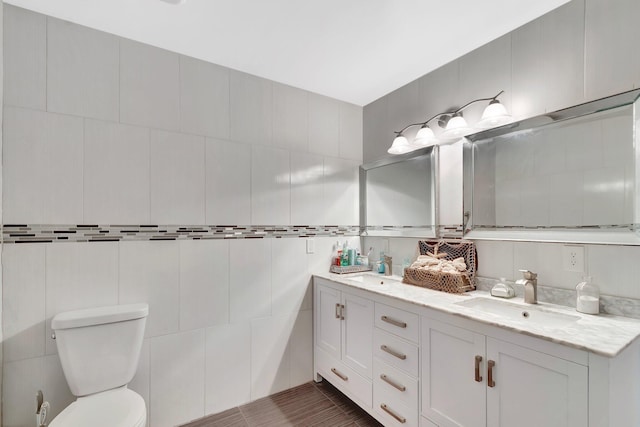 full bathroom featuring a sink, toilet, tile walls, and double vanity