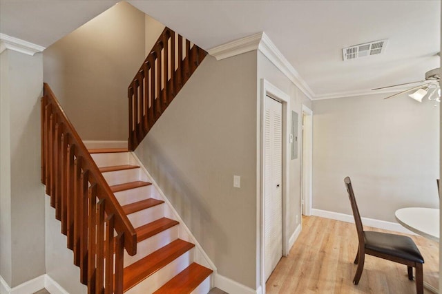 stairs featuring visible vents, wood finished floors, ornamental molding, and a ceiling fan