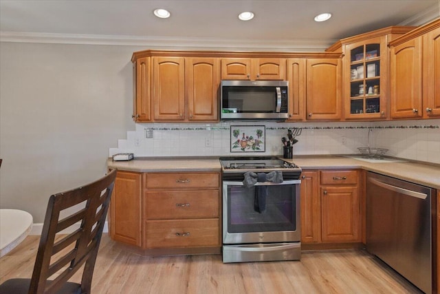 kitchen with a sink, light countertops, ornamental molding, and stainless steel appliances