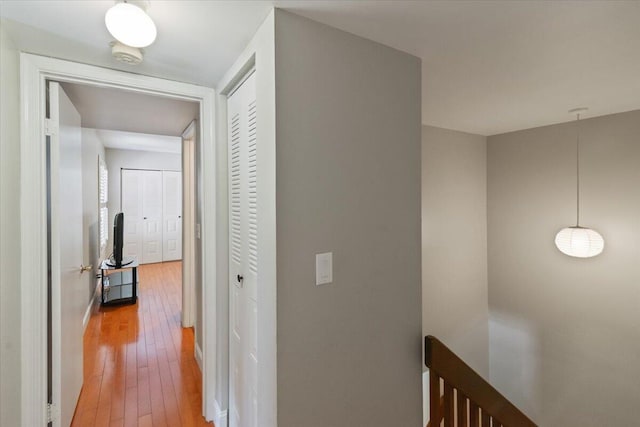 hall with an upstairs landing and light wood finished floors