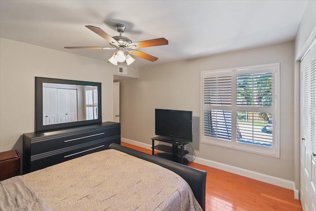 bedroom featuring wood finished floors, baseboards, visible vents, and a closet