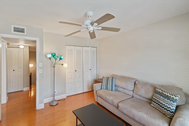 living room featuring baseboards, visible vents, a ceiling fan, and light wood-style floors