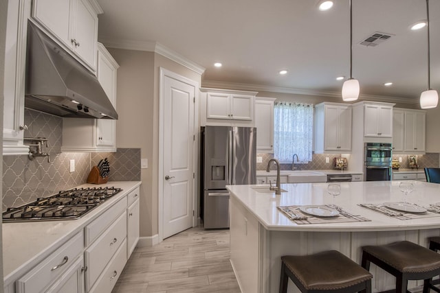 kitchen with visible vents, a sink, white cabinets, under cabinet range hood, and appliances with stainless steel finishes