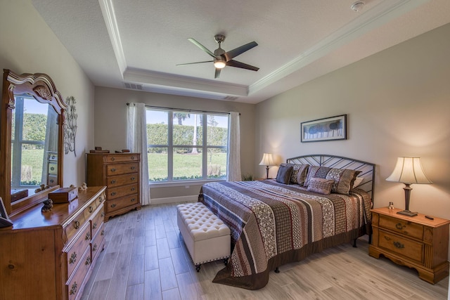 bedroom with visible vents, a raised ceiling, light wood-style floors, and a textured ceiling