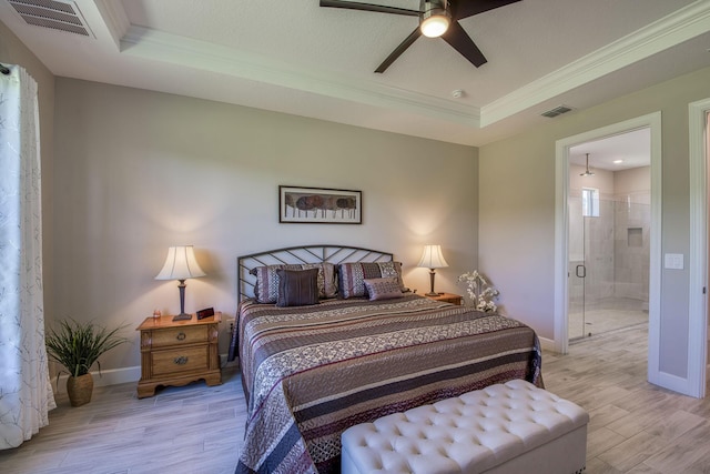 bedroom featuring visible vents, light wood finished floors, baseboards, a tray ceiling, and crown molding