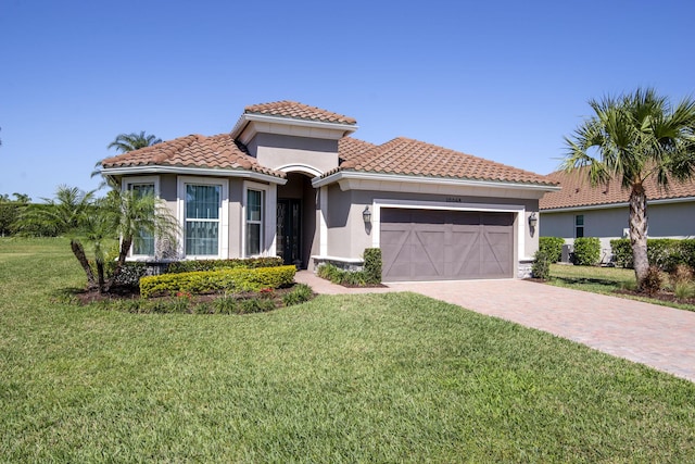 mediterranean / spanish-style house featuring stucco siding, driveway, a tile roof, a front yard, and an attached garage