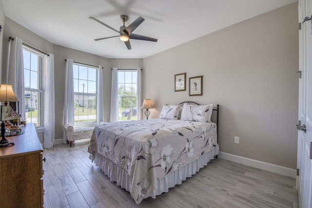 bedroom featuring baseboards, a ceiling fan, and light wood finished floors