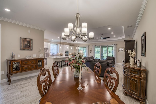 dining room with light wood-type flooring, visible vents, ornamental molding, and ceiling fan with notable chandelier