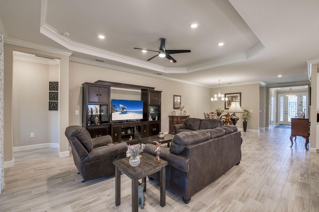 living area featuring ceiling fan with notable chandelier, a tray ceiling, light wood-style floors, crown molding, and baseboards