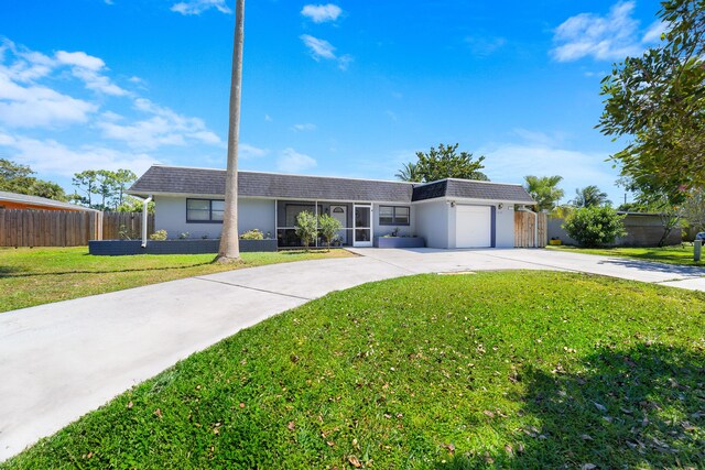 ranch-style house with concrete driveway, a garage, fence, and a front yard