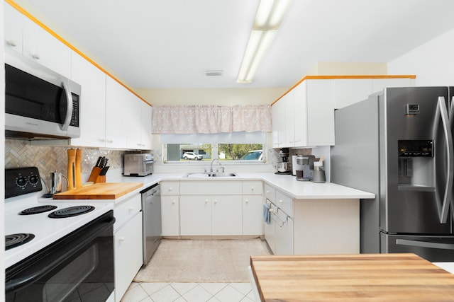 kitchen featuring a sink, white cabinetry, stainless steel appliances, light countertops, and decorative backsplash