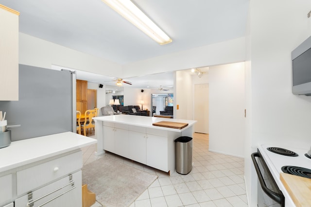 kitchen featuring a ceiling fan, light countertops, appliances with stainless steel finishes, white cabinetry, and open floor plan