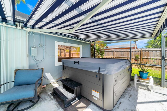 view of patio / terrace with a hot tub and fence