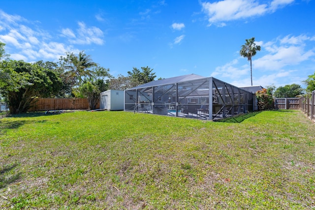 view of yard featuring a lanai, a storage unit, an outdoor structure, and a fenced backyard