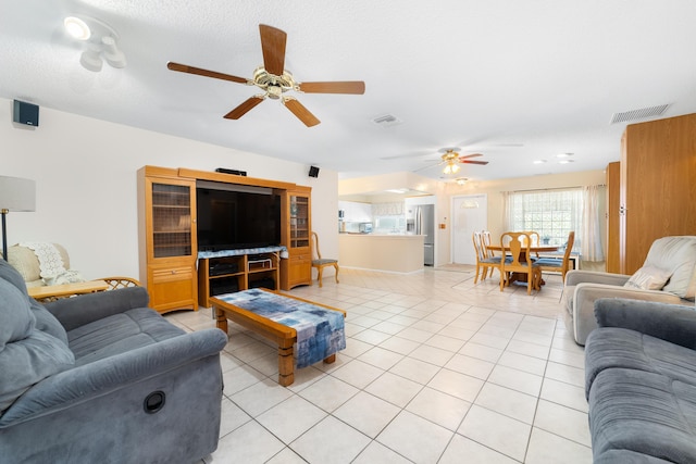 living room with light tile patterned floors, visible vents, a textured ceiling, and ceiling fan