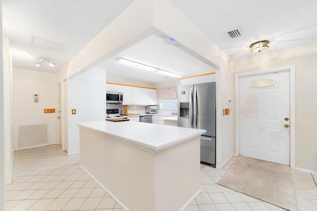 kitchen featuring visible vents, backsplash, light countertops, light tile patterned floors, and stainless steel appliances