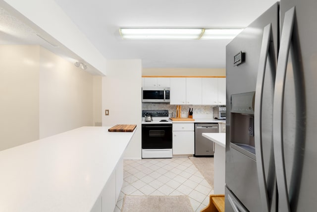 kitchen featuring light tile patterned flooring, light countertops, white cabinets, appliances with stainless steel finishes, and backsplash