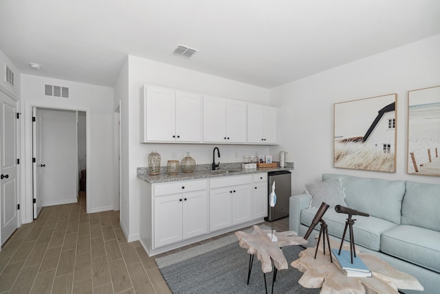 kitchen with white cabinetry, open floor plan, visible vents, and wood finish floors