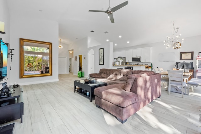 living area featuring baseboards, wood tiled floor, recessed lighting, ceiling fan with notable chandelier, and arched walkways