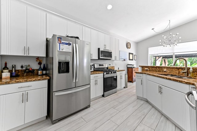 5822 Saddle Trail Ln, Lake Worth, FL 33449 - kitchen with appliances with stainless steel finishes, vaulted ceiling, a chandelier, white cabinetry, and dark stone counters