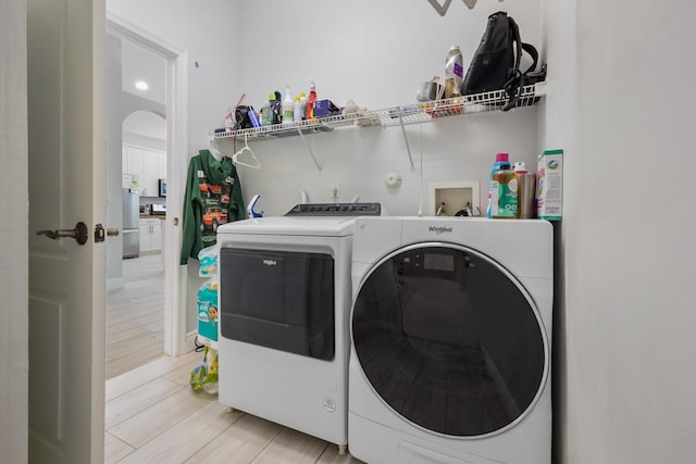 clothes washing area featuring laundry area, washing machine and dryer, and wood tiled floor