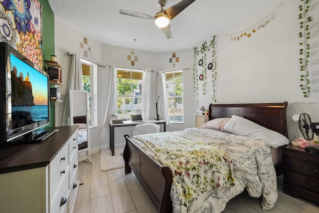 bedroom with light wood-style flooring, a ceiling fan, and baseboards