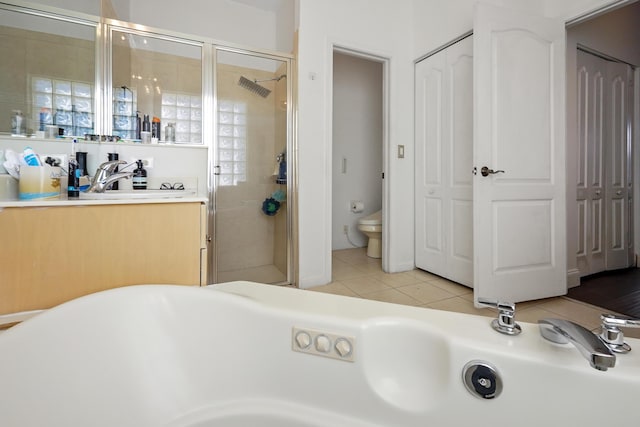 bathroom featuring tile patterned flooring, a freestanding tub, toilet, and a stall shower