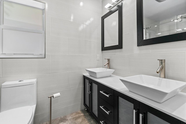 bathroom featuring tile walls, toilet, double vanity, and a sink