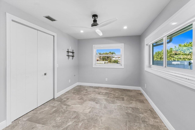 unfurnished bedroom featuring multiple windows, baseboards, visible vents, and a closet