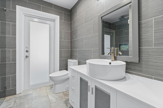 full bathroom with tile patterned flooring, toilet, tile walls, and vanity