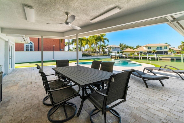 view of patio / terrace with outdoor dining area, fence, a ceiling fan, and a pool with connected hot tub