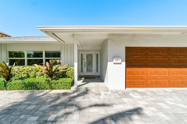 doorway to property with a garage and stucco siding