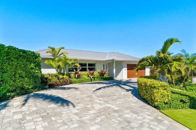 single story home with stucco siding, driveway, metal roof, and a garage