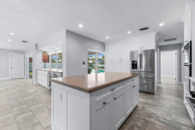 kitchen featuring a kitchen island, visible vents, appliances with stainless steel finishes, and white cabinetry