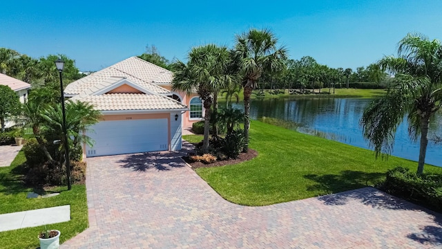 view of front of property with a front lawn, a water view, a tiled roof, a garage, and driveway