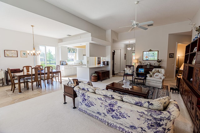 living area featuring ceiling fan with notable chandelier, visible vents, and light carpet