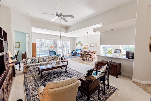 living area with a ceiling fan, baseboards, and a textured ceiling