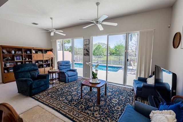 living room with carpet flooring, a ceiling fan, visible vents, and a textured ceiling