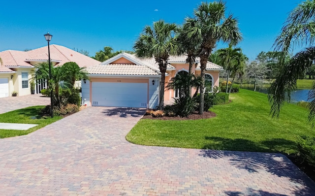 mediterranean / spanish-style home featuring driveway, an attached garage, stucco siding, a front lawn, and a tile roof