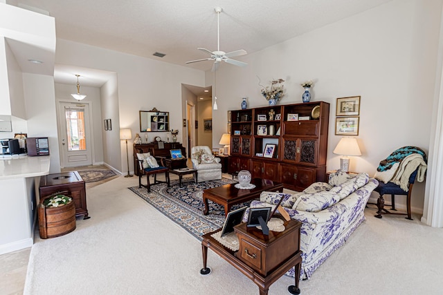 living area with visible vents, a ceiling fan, baseboards, and light carpet