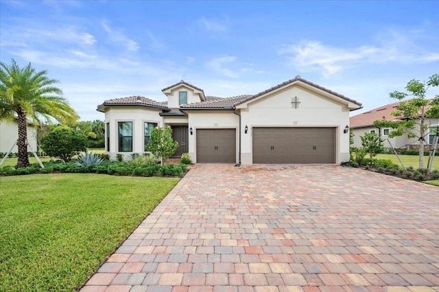 mediterranean / spanish-style home with a tile roof, a front yard, stucco siding, decorative driveway, and a garage