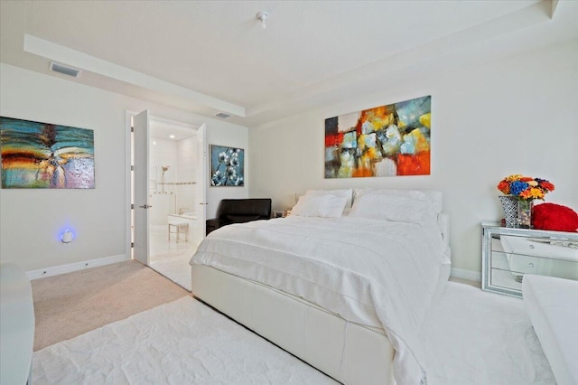 carpeted bedroom featuring a tray ceiling, baseboards, visible vents, and ensuite bath