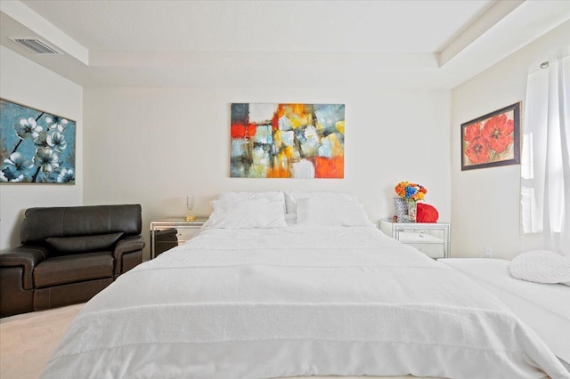 bedroom with a tray ceiling and visible vents