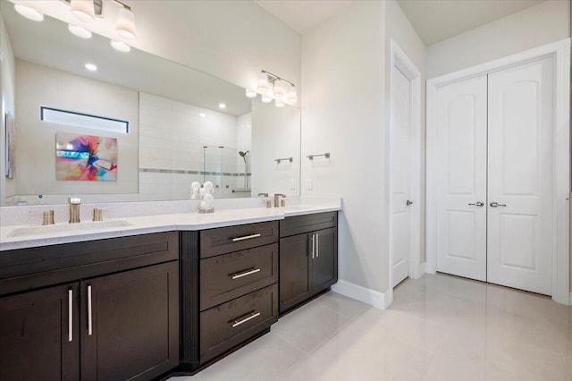 bathroom with baseboards, double vanity, a stall shower, a sink, and tile patterned floors