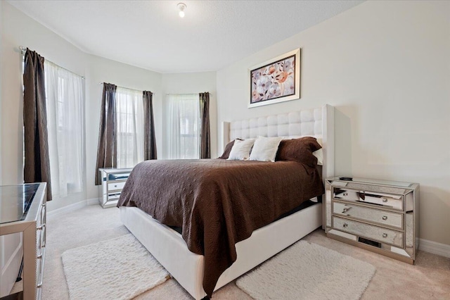 bedroom with light colored carpet and baseboards