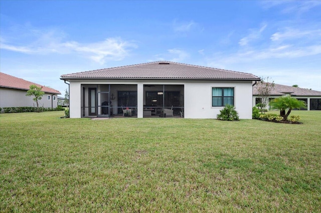 back of house with stucco siding, a sunroom, a lawn, and a tile roof