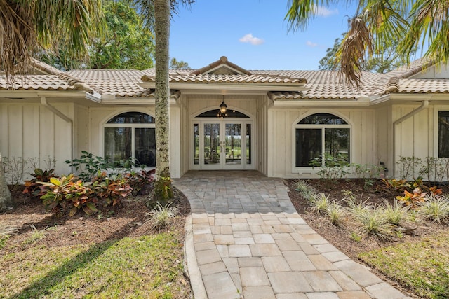 property entrance featuring french doors, board and batten siding, and a tiled roof